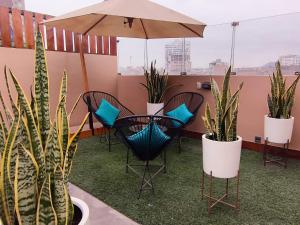 a patio with chairs and potted plants and an umbrella at Hotel Brickell in Lima