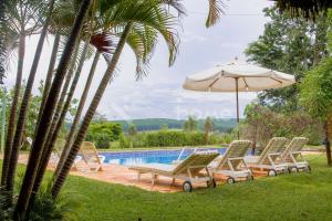 un grupo de sillas y una sombrilla junto a la piscina en Casa em condomínio com piscina e acesso a represa, en Itaí