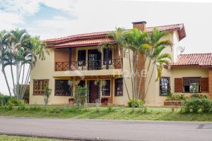 una casa con palmeras frente a una calle en Casa em condomínio com piscina e acesso a represa, en Itaí