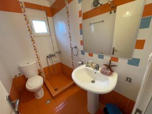 ein Badezimmer mit einem Waschbecken, einem WC und einem Spiegel in der Unterkunft Junis SeaSide Private Villa in Sarandë