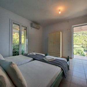 a bedroom with two beds and a large window at NIKOS APARTMENTS and PENTHOUSE in Vasiliki
