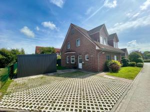 a brick house with a gate in the driveway at Möwennest in Krummhörn