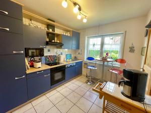 a kitchen with blue cabinets and a large window at Möwennest in Krummhörn +11 photos