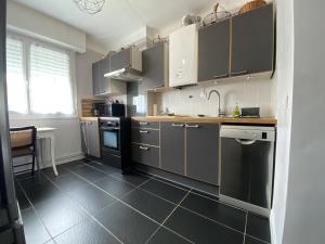 a kitchen with gray cabinets and a black floor at La barthe in Biarritz +12 photos