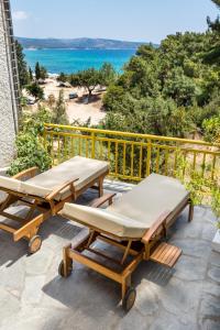 2 picknicktafels en banken op een balkon met uitzicht op de oceaan bij Rodon House Aparthotel in Limenaria