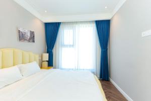 una camera da letto con un grande letto con tende blu di Altara Apartment Quy Nhon a Quy Nhon