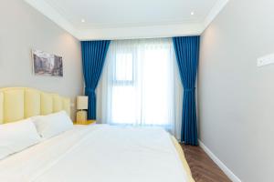 a bedroom with a large bed with blue curtains at Altara Apartment Quy Nhon in Quy Nhon