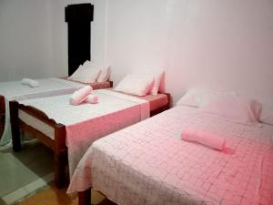two beds in a room with pink sheets at SEASCAPE in Moalboal