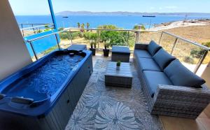 una gran bañera de hidromasaje azul en un balcón con sofá en PORTO D'ORO LUXURY APARTMENT, en Lávrion