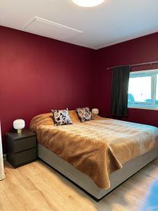 a bedroom with a large bed with red walls at Bergen Bliss: Mountain View in Bergen