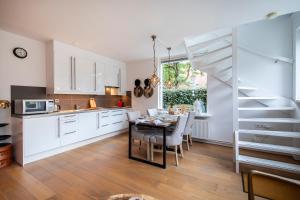 a kitchen and dining room with white cabinets and a table at Vakantiehuis De Zeeparel in Zandvoort