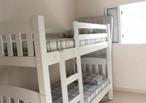 deux lits superposés blancs dans une pièce avec une fenêtre dans l'établissement Chácara Santa Luzia, à Socorro 50 autres photos