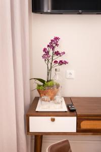 a table with a vase with purple flowers in it at Quinta dos Tojais in Celorico de Basto