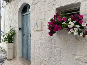 ein Gebäude mit einem Fenster mit Blumen und einer blauen Tür in der Unterkunft Bianco Calce - Ostuni in Ostuni