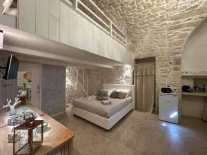 een slaapkamer met een wit bed en een stenen muur bij Bianco Calce - Ostuni in Ostuni