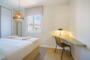 a bedroom with a bed and a desk and a window at Sitges Spaces Mediterranean Penthouse in Sitges