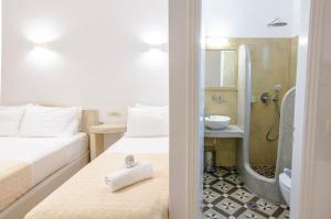 two beds in a room with a shower and a sink at Phevos Villa in Perissa