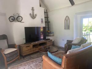 uma sala de estar com uma televisão de ecrã plano e cadeiras em Downrow Barn em Tintagel