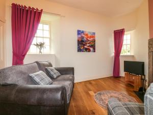 a living room with a couch and a tv at Holly Leaf Cottage - Drum Castle Estate in Banchory