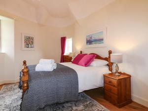 a bedroom with a bed with white sheets and pink pillows at Holly Leaf Cottage - Drum Castle Estate in Banchory