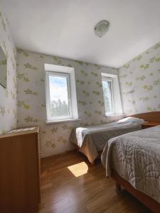 a bedroom with two beds and two windows at Apartment Jūros Mėlis in Nida