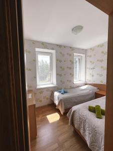 a bedroom with two beds and two windows at Apartment Jūros Mėlis in Nida