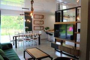 Una sala de estar con televisión y un comedor. en BetullaHouse, en Nakielno