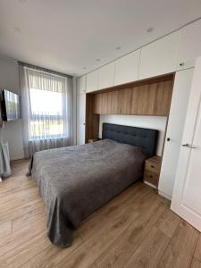 a bedroom with a large bed and a wooden floor at Ravėlino Apartment in Klaipėda