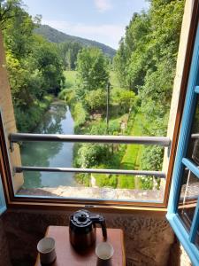 uma chaleira de chá numa mesa com vista para um rio através de uma janela em Chambre au moulin sur Aveyron em La Rouquette