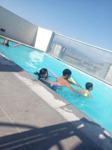 three children are playing in a swimming pool at Departamento Equipado (Estación Central) in Santiago