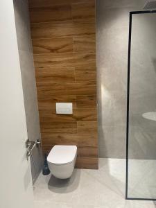 a bathroom with a toilet and a wooden wall at Emi Apartment in Durrës