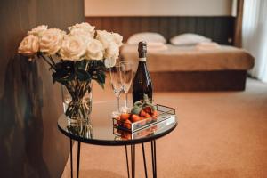 uma mesa com uma garrafa de vinho, flores e copos em Rytebłota Resort & Spa em Zbiczno