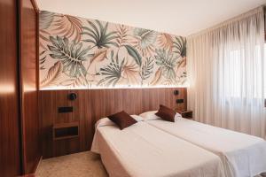 a bedroom with a bed and a wall with a mural at Hotel Xunqueira in Portonovo