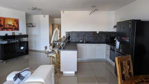 uma cozinha com armários brancos e electrodomésticos pretos em Appartement TUWA em Koungou