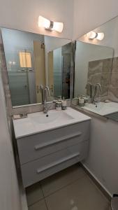 uma casa de banho com dois lavatórios e dois espelhos em Appartement TUWA em Koungou