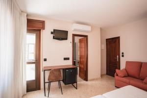 a living room with a couch and a tv on the wall at Hotel Xunqueira in Portonovo