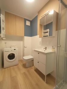 y baño con lavamanos y lavadora. en Apartament Stogi en Gdansk