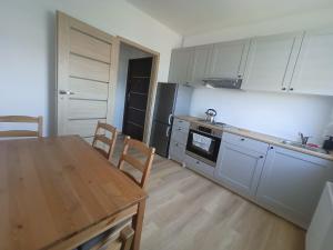 a kitchen with white cabinets and a table and chairs at Apartament Stogi in Gdańsk