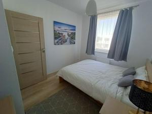 a small bedroom with a bed and a window at Apartament Stogi in Gdańsk