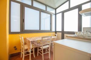 a kitchen with a table and chairs and windows at Royal Playa Suite and Apartament -private parking- self chek out in Catania
