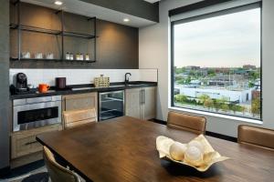 a kitchen with a wooden table and a large window at The Trade, Autograph Collection in Milwaukee