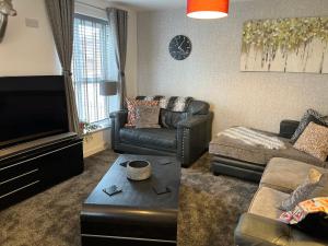 a living room with a couch and a tv at Lovely 3 bed house near Anfield Stadium with private parking and garden Guests must be 25 years or over to make a booking in Liverpool