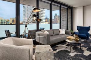 a living room with a couch and chairs and a large window at The Trade, Autograph Collection in Milwaukee