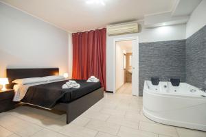 a bedroom with a bed and a tub in a room at Royal Playa Suite and Apartament -private parking- self chek out in Catania