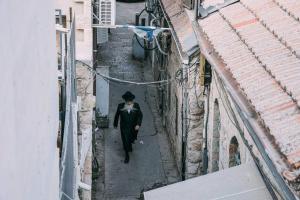 een man in een pak en hoed die door een steegje loopt bij New. Center town. Superb appartment. in Jeruzalem