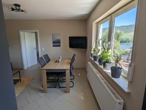 ein Esszimmer mit einem Tisch, Stühlen und Fenstern in der Unterkunft Ferienwohnung Rheinperle in Niederheimbach