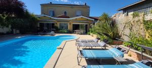 a swimming pool with chairs and a house at Bienvenue chez Lilaroma in Mérignac