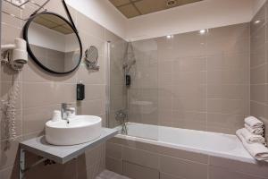 a bathroom with a sink and a tub and a mirror at The Originals Boutique, Hôtel Danieli, Avignon in Avignon