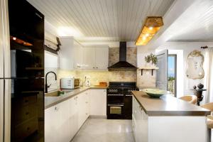 ArvanitakaíïkaにあるVilla Ianiraのキッチン(白いキャビネット、黒いコンロ付)