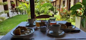 einen Tisch mit Teller mit Speisen und Tassen Kaffee in der Unterkunft Pousada Maria Maria Búzios in Búzios